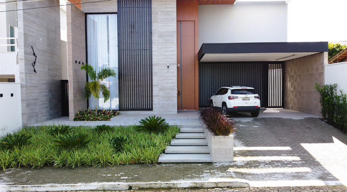 Refúgio Tropical: Paisagismo Minimalista Valoriza Residência em Sapucaia-RJ Paisagismo residencial por Studio Julio Sousa Paisagista| Fachada da casa com canteiro de pinheiros-de-buda