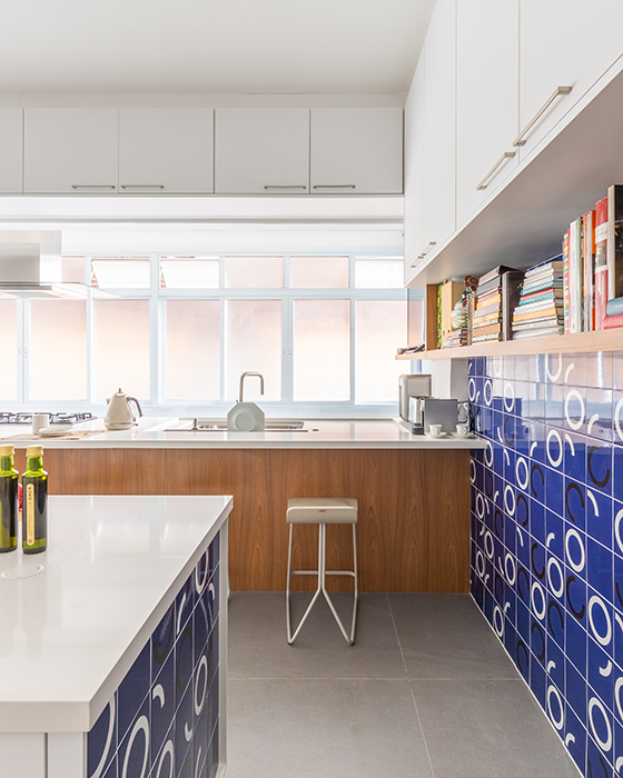 Inspirada nos anos 1970, esta cozinha assinada por Bruno Moraes traz o colorido de forma equilibrada. A base neutra em branco destaca a cerâmica azul com detalhes em preto e branco, conferindo personalidade ao projeto | Projeto BMA Studio