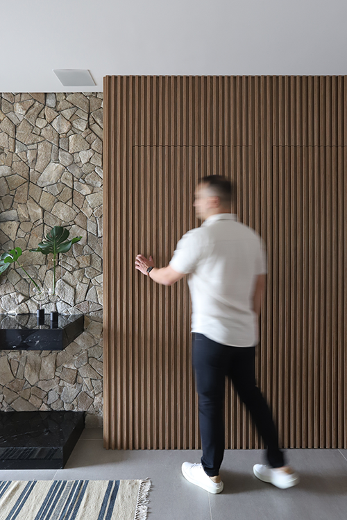 Camuflada no painel ripado, a portas mimetizadas concebidas pelo arquiteto Bruno Moraes resguardam a entrada do lavabo e do dormitório