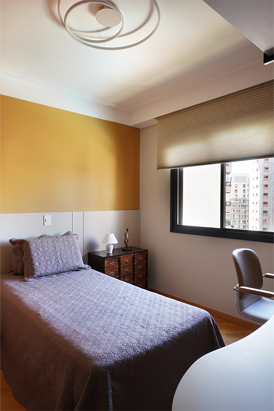 No home office com a mesa em formato orgânico, o painel de madeira com as prateleiras suportadas pela serralheria preta ajuda a manter os itens sempre organizados. Por lá, a cama está sempre pronta para receber os hóspedes com total comodidade | Projeto: Rosangela Pena Arquitetura
