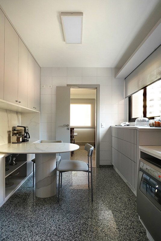 Enquanto o piso da cozinha acompanha a estética do granilite, o restante da paleta de cores da cozinha mantém os tons neutros, com ênfase na leveza do cinza | Projeto: Rosangela Pena Arquitetura