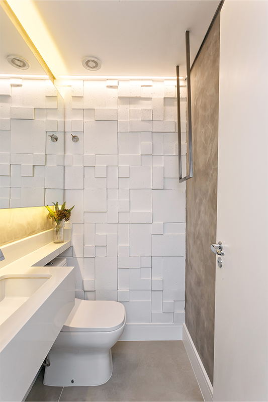 Projeto: RMV Interiores | No lavabo, cimento queimado, revestimento 3D e suporte de toalha em serralheria criam um ambiente urbano e ousado, com iluminação difusa.