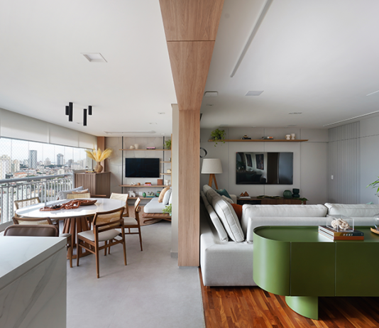 Reforma de apartamento explora dimensões generosas da varanda e agrega soluções como a inserção de um passa-prato na cozinha Projeto: Rosangela Pena Arquitetura | Entre a sala de estar e a varanda, a arquiteta Rosangela Pena valorizou a viga existente ao revesti-la com madeira. A 'divisão' sutil entre os ambientes tornou-se ainda mais elegante.