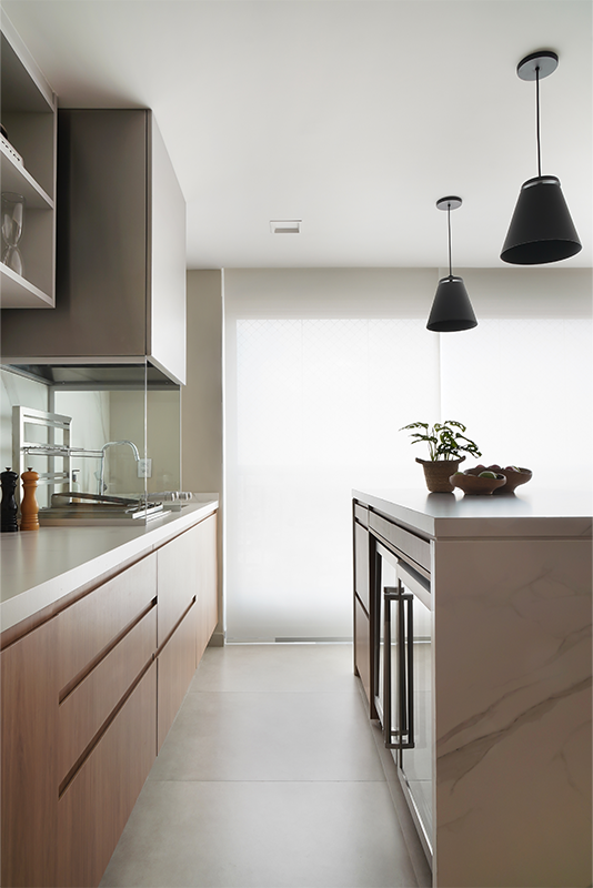 Projeto: Rosangela Pena Arquitetura | Na área gourmet, a marcenaria assinada por Rosangela Pena traz puxadores cava, discretos e funcionais. A bancada com banquetas aproxima o casal dos convidados e serve como apoio prático durante as refeições.
