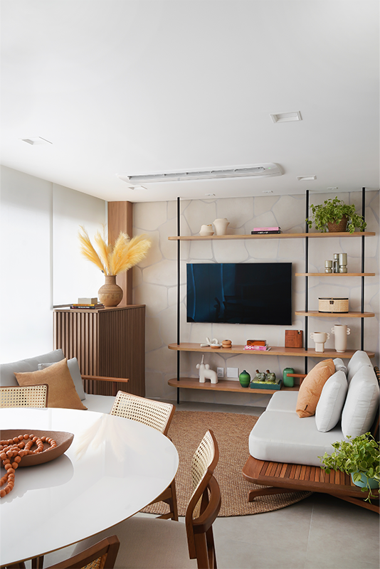Projeto: Rosangela Pena Arquitetura | Serralheria e madeira se unem na parede para formar uma estante minimalista que dá leveza à TV, fixada em um painel de porcelanato orgânico instalado peça por peça.