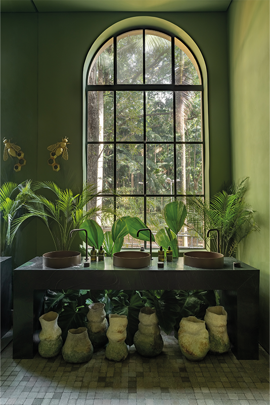 Projeto: Traço 8 | Paisagismo: Casa K Paisagismo | Vasos da coleção Jardim de Corais, criados por Alisson Silva, se destacam sobre a bancada, unindo ancestralidade, arte e consciência ambiental. As peças feitas com argila branca e técnicas sustentáveis dialogam com o paisagismo e a paleta terrosa, criando uma experiência sensorial e imersiva no ambiente da CASACOR.