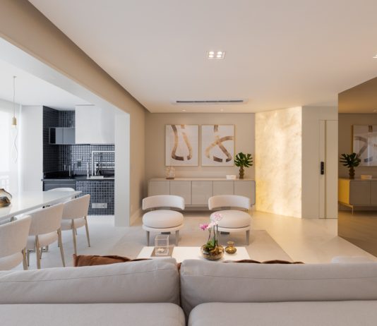 Aconchego sem madeira em apartamento sofisticado criado por Sabrina Salles Projeto: Sabrina Salles | Sala de jantar ganha sofisticação com buffet em pedra translúcida iluminada lateralmente e cristaleira bar em vidro reflecta.