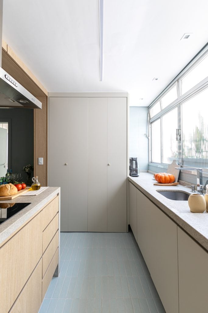 Projeto: Bima Arquitetura | A cozinha com novo layout reorganiza os ambientes, inserindo a lavanderia oculta dentro de um armário.