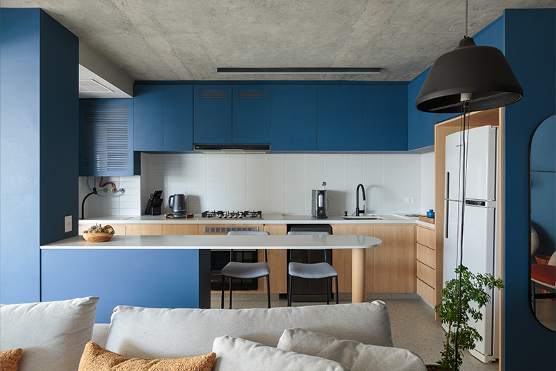 Projeto: Estúdio Maré | O contraste entre concreto aparente no teto e azul vibrante valoriza a cozinha.
