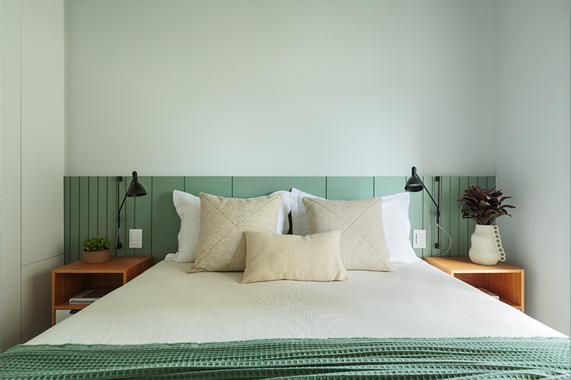 Projeto: Estúdio Maré | A rusticidade do concreto aparente ganha suavidade com a cabeceira em marcenaria colorida; já o armário neutro traz equilíbrio e leveza ao quarto.