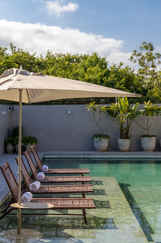 Projeto: Érica Salguero | Piscina, churrasqueira integrada e mobiliário generoso formam o coração da casa, ideal para receber amigos e familiares com conforto e estilo.