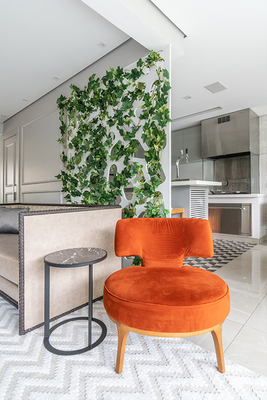 Projeto: Sabrina Salles | A estante em serralheria substitui o antigo biombo, criando uma divisão leve entre o living e a churrasqueira, além de expor memórias afetivas e objetos decorativos.