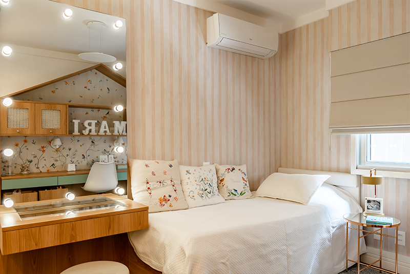 Projeto: Juliana Fabrizzi | Lúdico e funcional, o espaço traz escrivaninha em formato de casinha, baús volantes e penteadeira com luzes — um cenário cheio de afeto e imaginação.