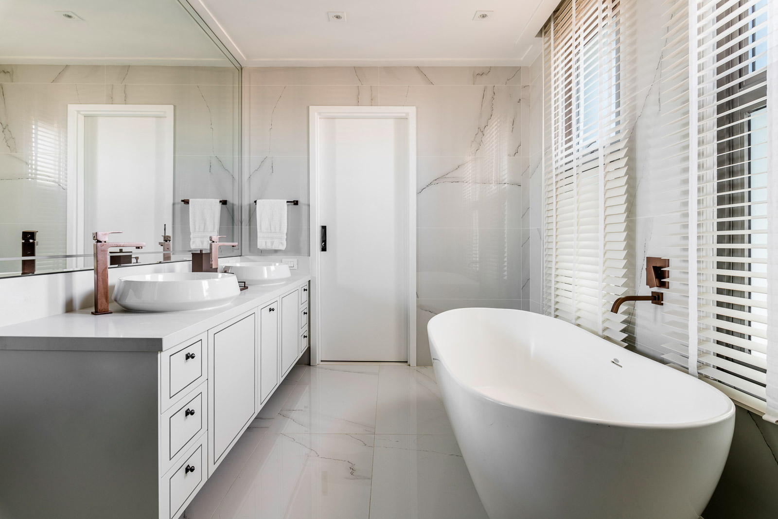 Banheiro adaptado para casal com banheira, duas pias e armário largo para armazenar