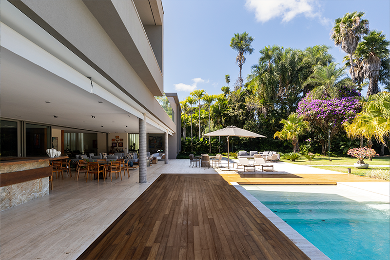 Diferentes cores, alturas e texturas de espécies compõem o jardim com piscina e área de convivência.