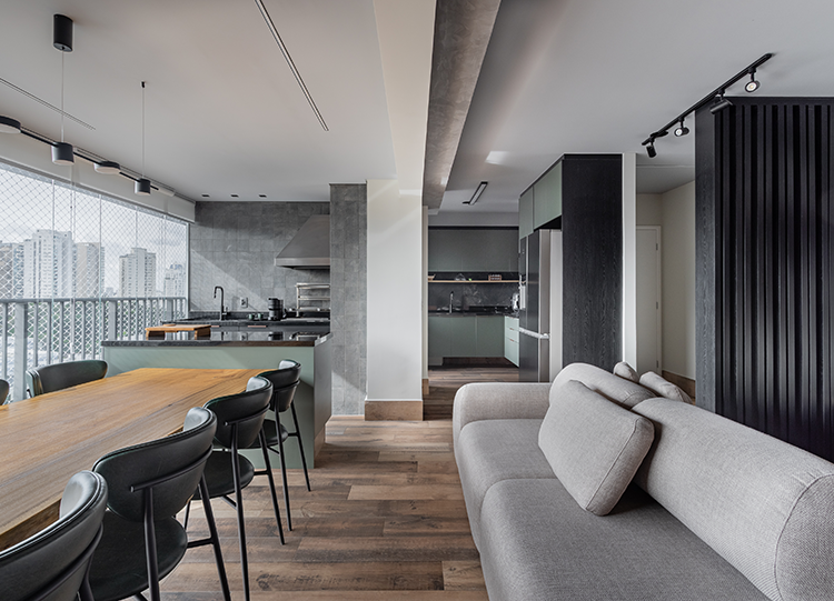 Projeto: Camila Palladino| Integração total do living com a varanda gourmet, criando um grande ambiente social marcado por tons de cinza, preto e acentos das cadeiras em verde.