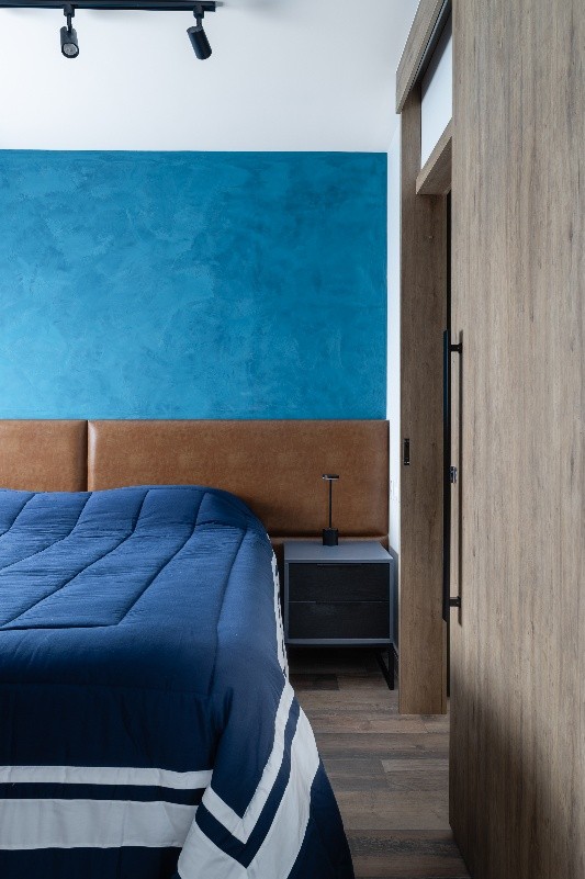 Projeto: Camila Palladino| Neste quarto a parede em azul profundo texturizado, cabeceira em couro caramelo e iluminação suave criam uma suíte sensorial e acolhedora. Além de um closet amplo para maior funcionalidade no dia a dia.