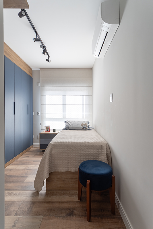 Projeto: Camila Palladino| Suíte funcional com home office: marcenaria contínua organiza bancada, armários e nichos; paleta em azul profundo, cinza e branco traz leveza e foco