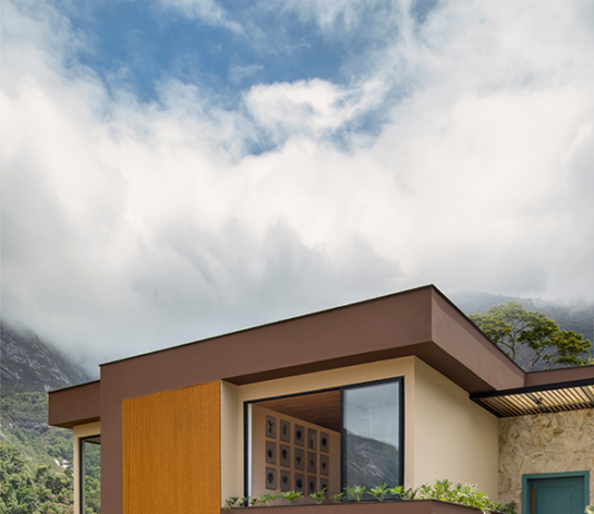 Casa colonial renasce como lar contemporâneo em meio ao verde da serra Projeto: Felipe Rohen Arquitetura | Antes e depois da fachada: a antiga construção colonial de tijolinhos deu lugar a uma nova linguagem contemporânea, marcada por linhas retas, pedras naturais e portas em azul vibrante.