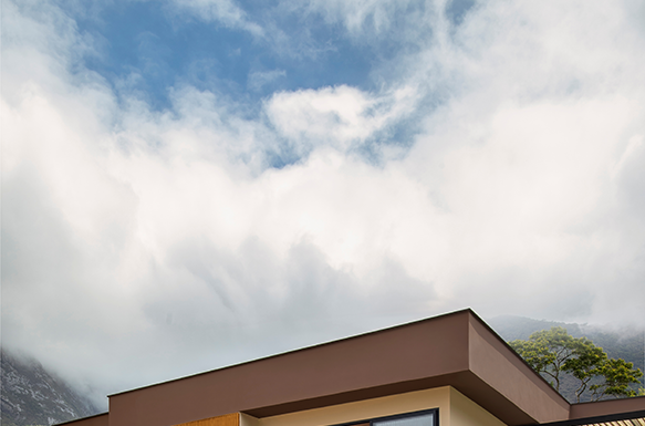 Casa colonial renasce como lar contemporâneo em meio ao verde da serra Projeto: Felipe Rohen Arquitetura | Antes e depois da fachada: a antiga construção colonial de tijolinhos deu lugar a uma nova linguagem contemporânea, marcada por linhas retas, pedras naturais e portas em azul vibrante.