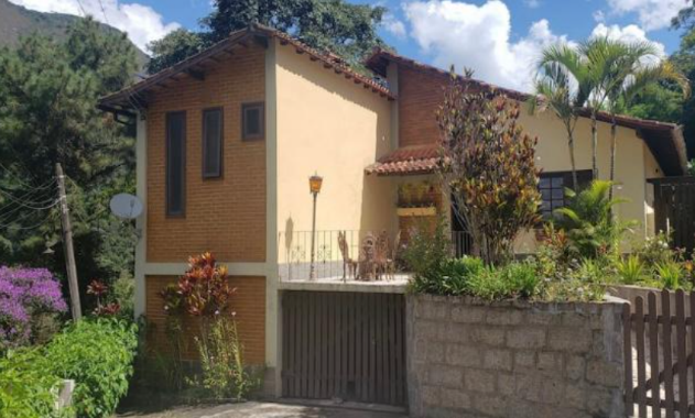 Projeto: Felipe Rohen Arquitetura | Antes e depois da fachada: a antiga construção colonial de tijolinhos deu lugar a uma nova linguagem contemporânea, marcada por linhas retas, pedras naturais e portas em azul vibrante.