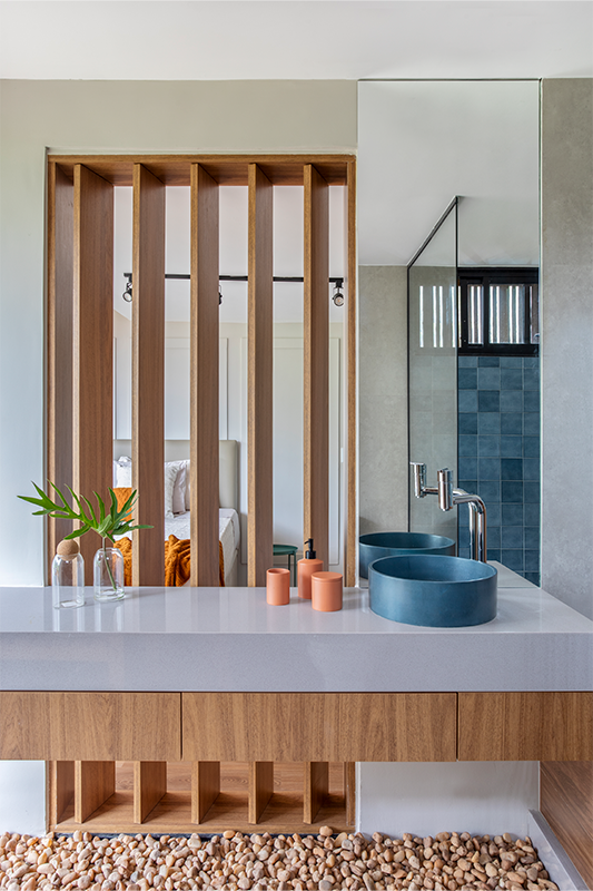 Projeto: Felipe Rohen Arquitetura | A suíte do casal ganhou atmosfera de hotel, com banheiro integrado, porcelanato azul e um delicado canteiro de seixos que reforça o vínculo com a natureza.