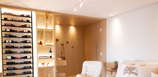 Arquiteta Carolina Oliveira assina reforma de Interiores e transforma apartamento de 77m² em refúgio acolhedor em Ubatuba, São Paulo, Brasil Projeto: Carolina Oliveira | A sala integrada com uma adega iluminada é a grande protagonista deste projeto.