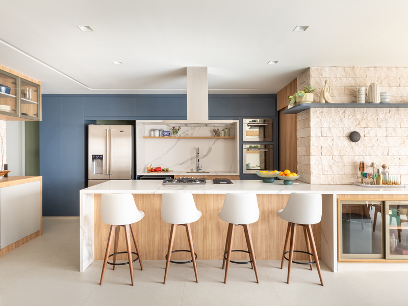 Pia e cooktop na ilha formam um triângulo eficiente com a geladeira ao fundo – Foto: Guilherme Pucci | Projeto: Bruno Moraes Arquitetura