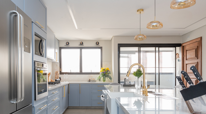 Juntas, porém delimitadas: a importância da oferecer a independência entre a cozinha e a área de serviço nos projetos residenciais Projeto Mari Milani| Cozinha ampla com ilha central e marcenaria em azul claro. A área de serviço fica integrada, mas discreta, graças à porta de serralheria com vidro canelado, garantindo luz natural e organização.