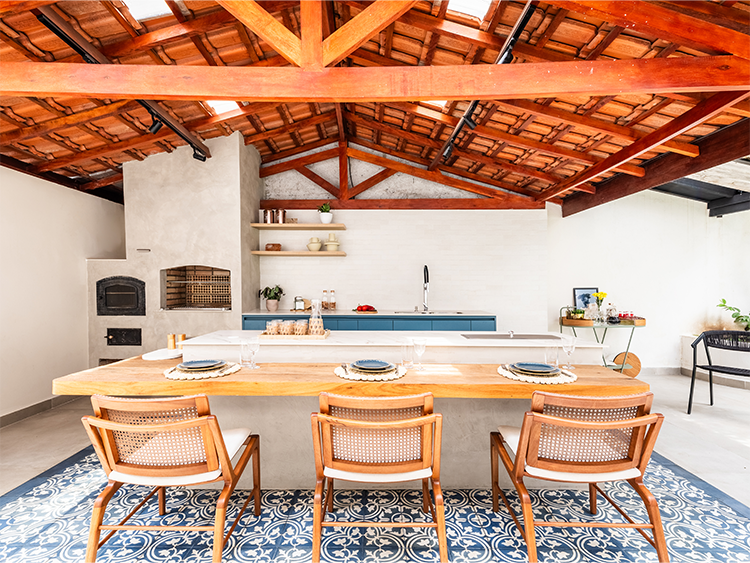 Coberta com telhas de barro, a unidade visual do sobrado é percebida com o azul presente na marcenaria e o piso onde está localizada a ilha 