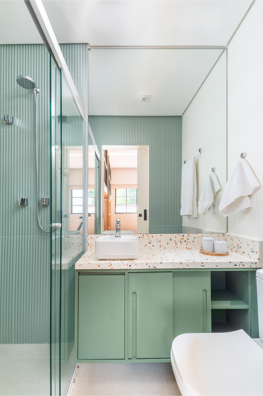 Um clima leve e descontraído com o verde avistado no revestimento interno do box e na marcenaria que expõe um importante detalhe: a substituição das portas de giro pelo modelo de correr, como estratégia para driblar a questão do pouco espaço existente no banheiro 