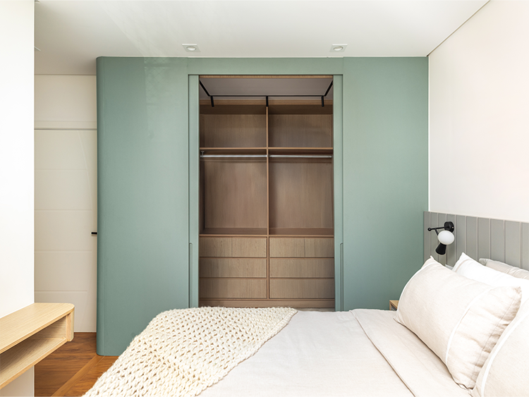 A suíte do casal aposta em marcenaria curva, cabeceira ripada e paleta neutra