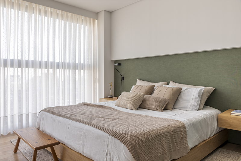 A sacada com fechamento acústico garante um sono tranquilo à noite. Além disso, luminárias de leitura foram postas em cada lado da cama 