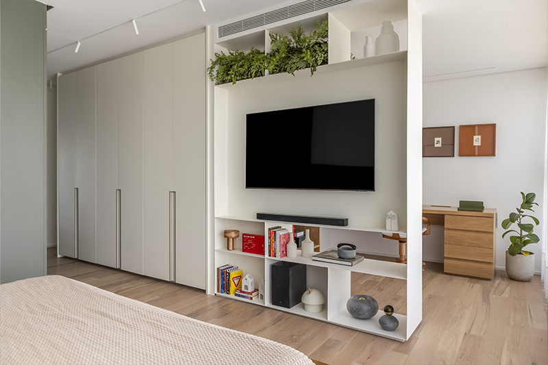 A serralheria off white divide a suíte do home office e serve de painel de TV 