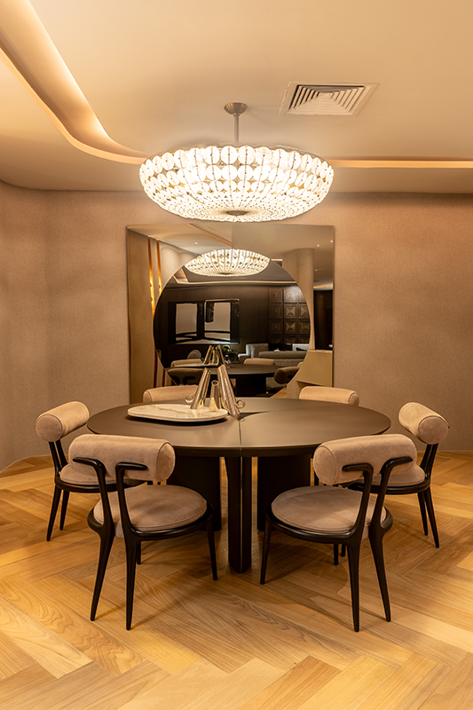 Em contraponto ao pendente de cristais de rocha, o piso de tauari claro tem a marcante e eterna paginação escama-de-peixe. A base neutra devidamente representada pelos tons de cinza e chumbo dos demais revestimentos, permite que o revestimento transmita as sensações de amplitude e aconchego à sala de jantar 