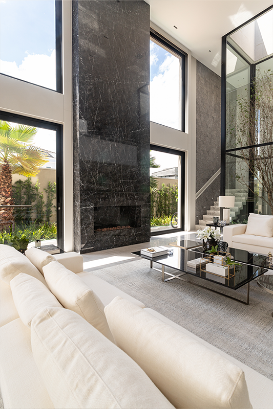 No projeto dessa residência assinada pela arquiteta Patricia Penna, o mármore natural foi eleito para revestir toda a parte da lareira do suntuoso living com pé-direito duplo 