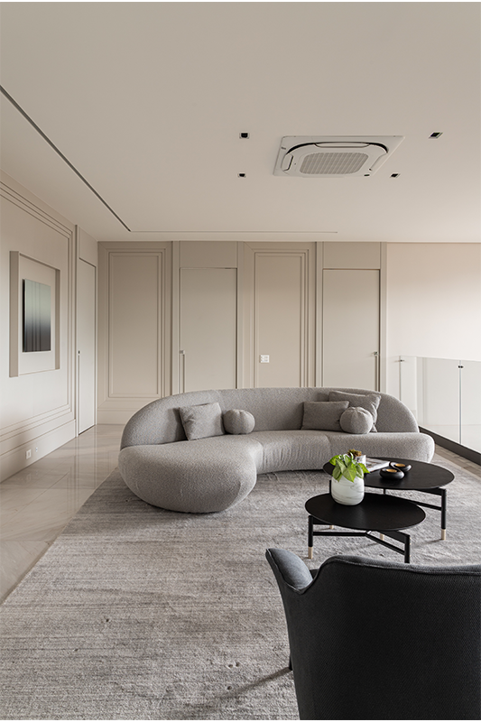 Nesta antessala residencial, o sofá curvo foi complementado por almofadas no mesmo tecido. Na elaboração do ambiente, duas poltronas orgânicas de espaldar baixo, além de mesas circulares, se somam com sutileza e requinte