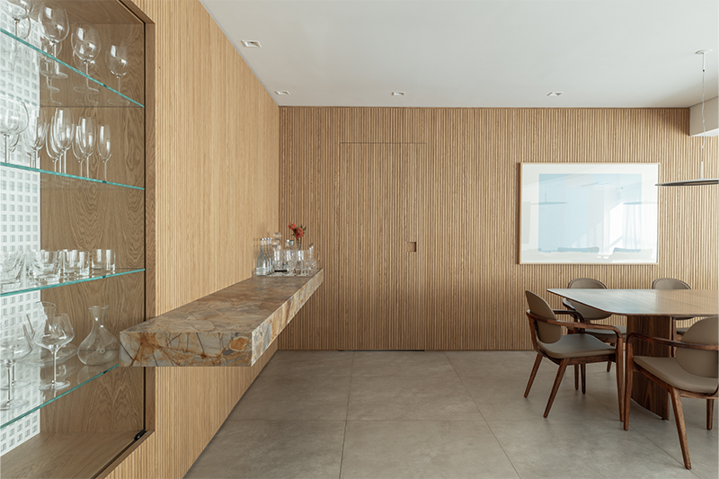 Painéis ripados em freijó natural aquecem a base neutra e trazem textura ao ambiente